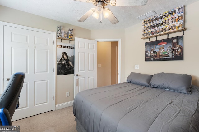 bedroom with a textured ceiling, light colored carpet, and ceiling fan