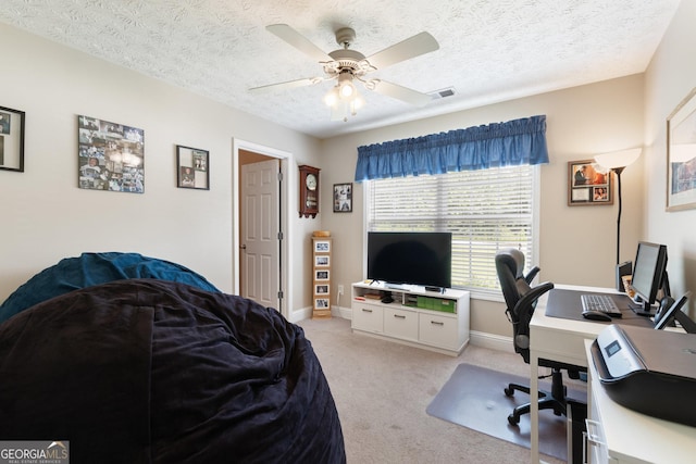 carpeted home office with ceiling fan and a textured ceiling