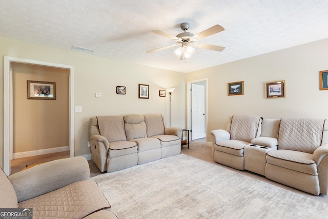 carpeted living room featuring ceiling fan and a textured ceiling