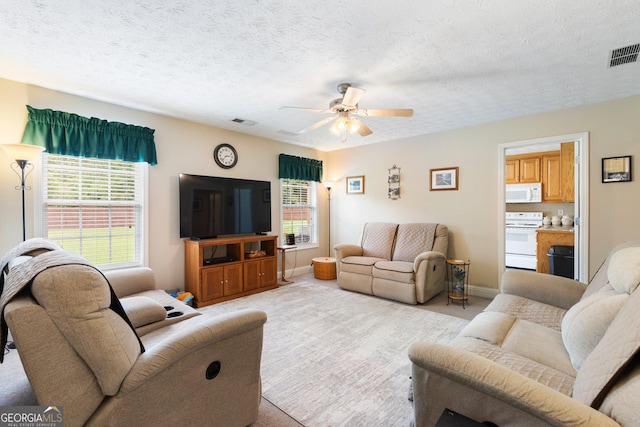 carpeted living room featuring ceiling fan and a textured ceiling