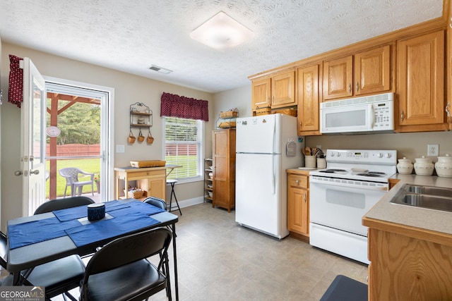 kitchen featuring a textured ceiling, white appliances, and sink