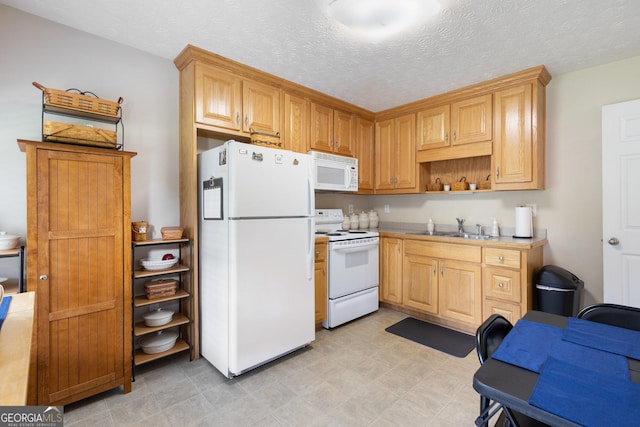 kitchen with a textured ceiling, white appliances, and sink