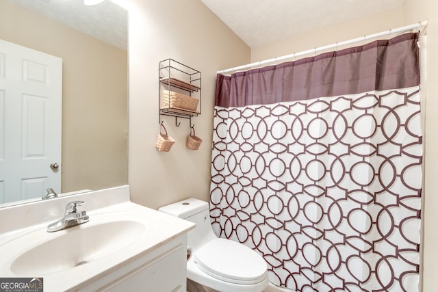 bathroom with vanity, curtained shower, toilet, and a textured ceiling