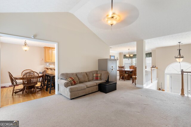 carpeted living room featuring vaulted ceiling and ceiling fan with notable chandelier