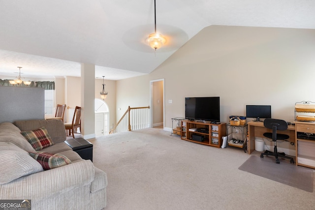 carpeted living room with ceiling fan with notable chandelier and lofted ceiling