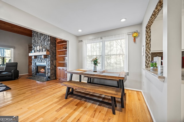 dining space with a fireplace, light hardwood / wood-style floors, built in features, and plenty of natural light