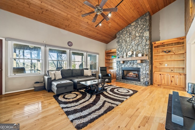 living room featuring wood ceiling, ceiling fan, light hardwood / wood-style flooring, high vaulted ceiling, and a stone fireplace