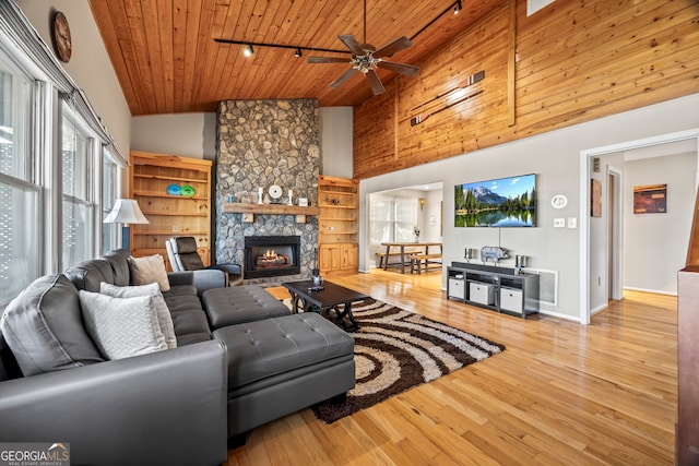 living room with light wood-type flooring, rail lighting, wood ceiling, high vaulted ceiling, and a fireplace