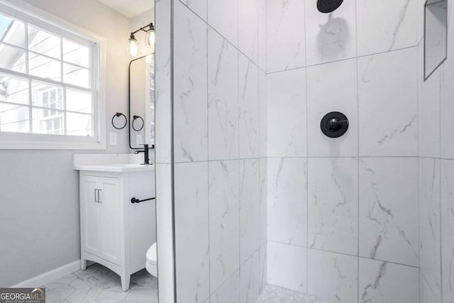 bathroom featuring toilet, vanity, and tiled shower