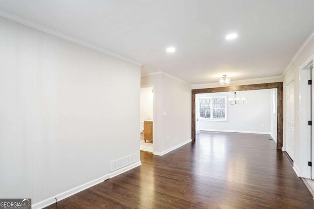 spare room with crown molding, dark hardwood / wood-style flooring, and a notable chandelier