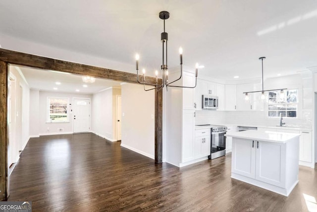 kitchen with pendant lighting, dark hardwood / wood-style floors, appliances with stainless steel finishes, a kitchen island, and white cabinetry