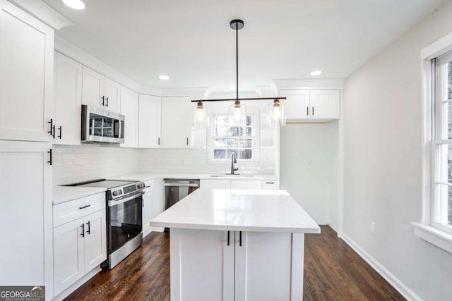 kitchen featuring appliances with stainless steel finishes, white cabinetry, and hanging light fixtures