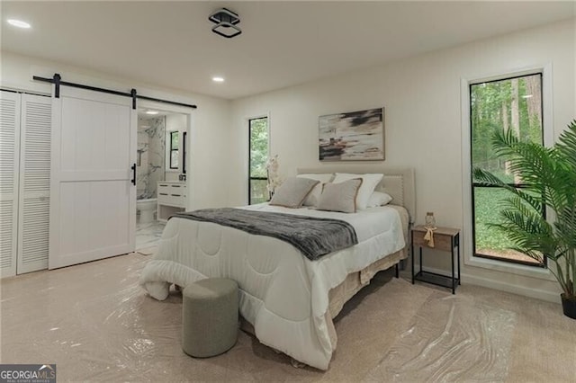 bedroom featuring a barn door and ensuite bath