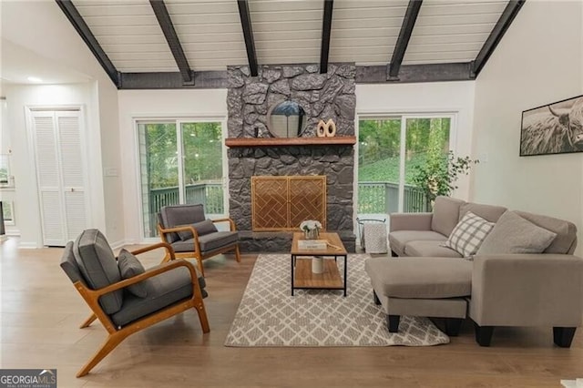 living room featuring vaulted ceiling with beams, a fireplace, and light hardwood / wood-style floors