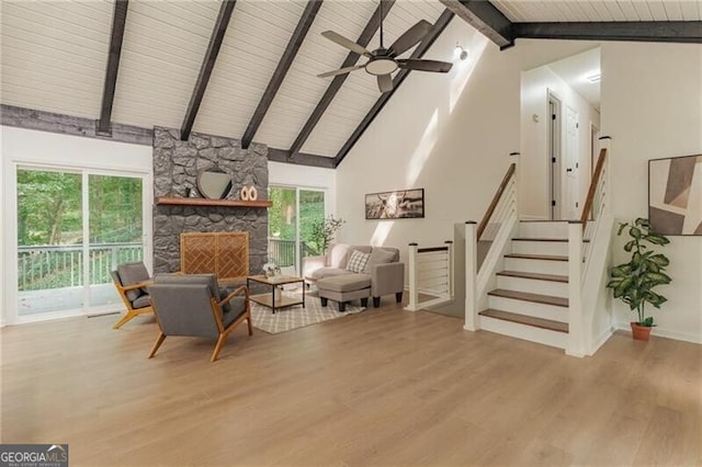 sitting room featuring light wood-type flooring, ceiling fan, high vaulted ceiling, beamed ceiling, and a fireplace