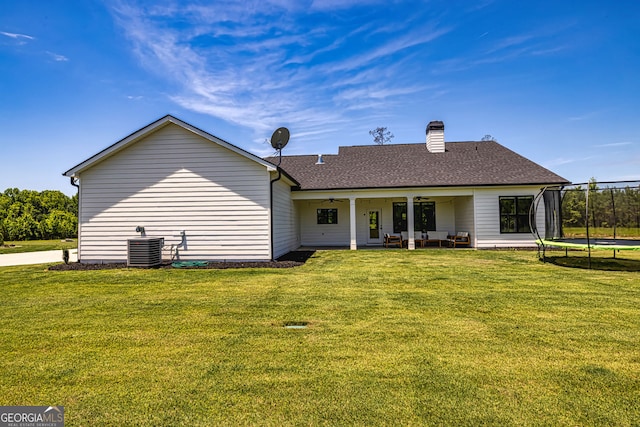 back of property featuring an outdoor hangout area, central air condition unit, ceiling fan, a trampoline, and a lawn