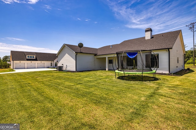 back of house featuring a lawn, a trampoline, and central AC