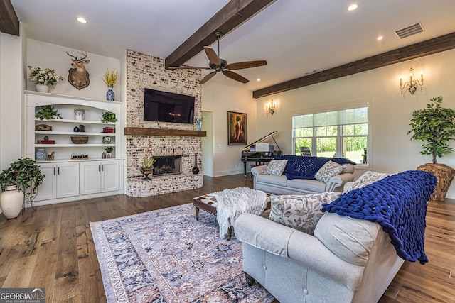 living room with ceiling fan, beam ceiling, dark hardwood / wood-style floors, and a brick fireplace