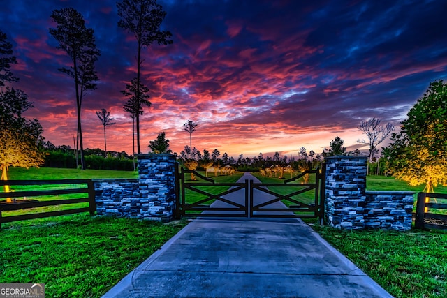 gate at dusk featuring a yard