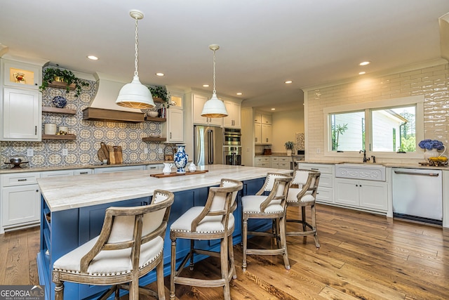 kitchen featuring a center island, sink, hanging light fixtures, white cabinetry, and stainless steel appliances