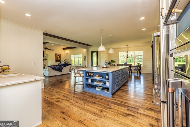 kitchen with sink, decorative light fixtures, blue cabinets, and light hardwood / wood-style flooring