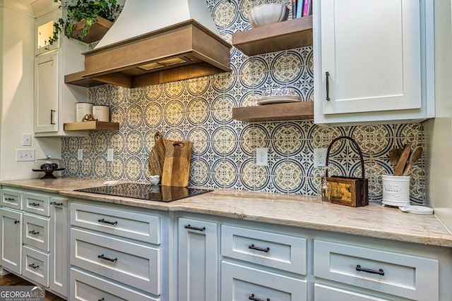 kitchen featuring custom range hood, backsplash, black electric cooktop, and white cabinetry