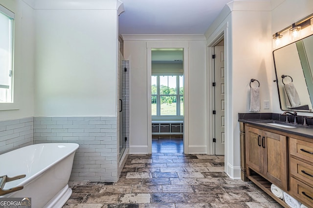 bathroom with separate shower and tub, vanity, and tile walls