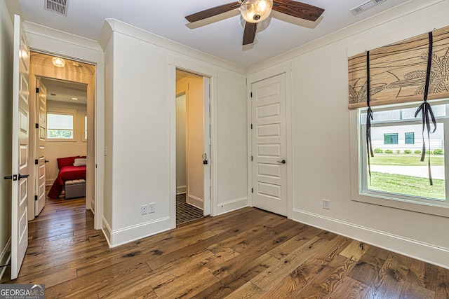 unfurnished bedroom with a closet, dark hardwood / wood-style floors, ceiling fan, and crown molding