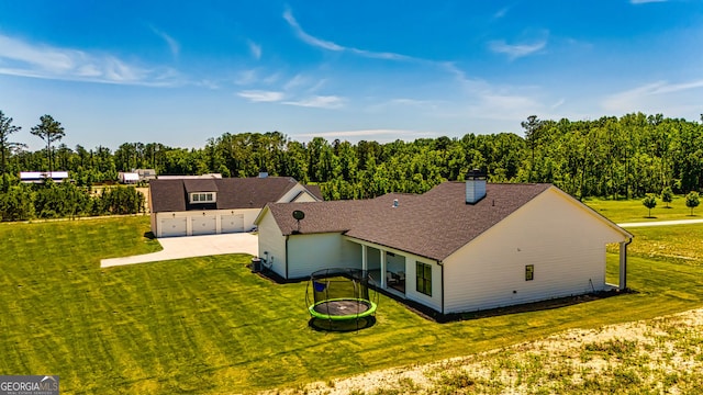 back of property featuring a lawn and a trampoline