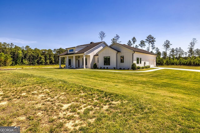 modern farmhouse featuring a porch, a garage, and a front lawn