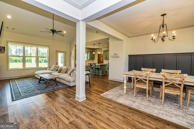 dining area featuring ceiling fan with notable chandelier, crown molding, and dark wood-type flooring