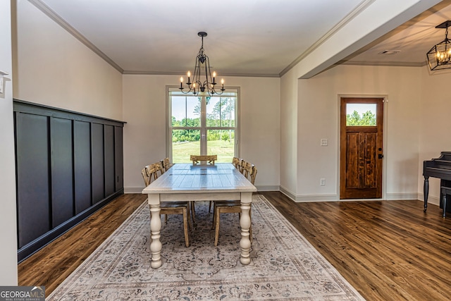 dining area with dark hardwood / wood-style floors, ornamental molding, and an inviting chandelier