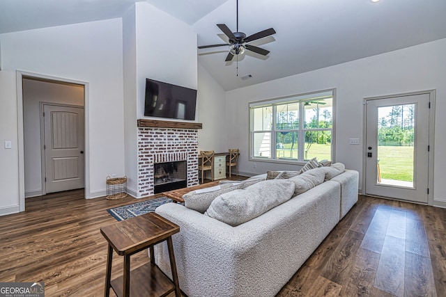 living room with ceiling fan, dark hardwood / wood-style flooring, high vaulted ceiling, and a brick fireplace