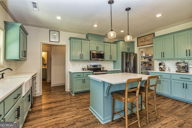 kitchen featuring appliances with stainless steel finishes, dark wood-type flooring, sink, pendant lighting, and a center island