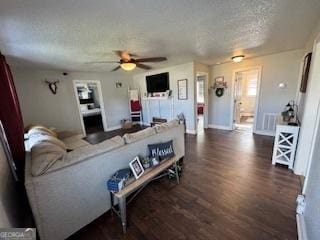 living room with dark hardwood / wood-style flooring, ceiling fan, and a textured ceiling