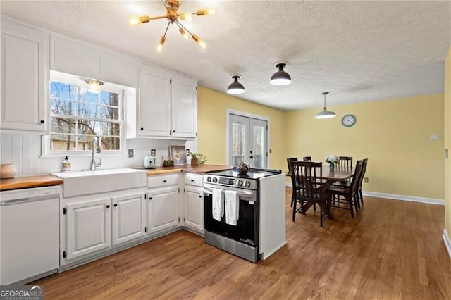 kitchen with dishwasher, sink, stainless steel stove, decorative backsplash, and white cabinetry