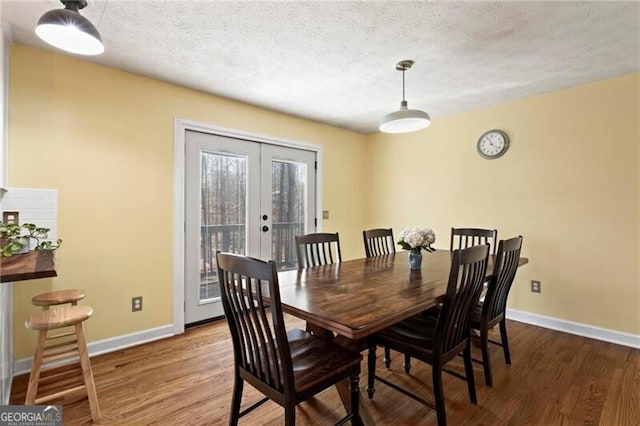 dining space featuring french doors, a textured ceiling, and hardwood / wood-style flooring