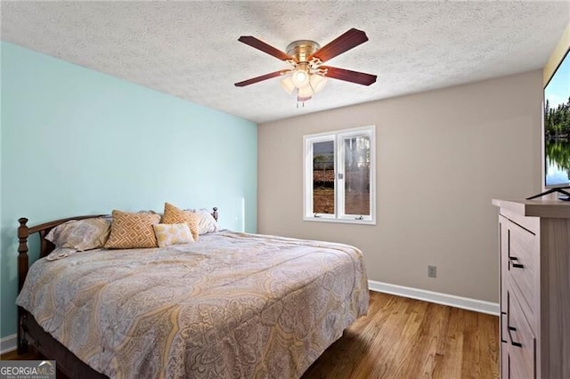 bedroom featuring hardwood / wood-style floors, a textured ceiling, and ceiling fan