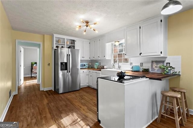 kitchen featuring wood counters, stainless steel refrigerator with ice dispenser, white cabinetry, dark hardwood / wood-style flooring, and kitchen peninsula