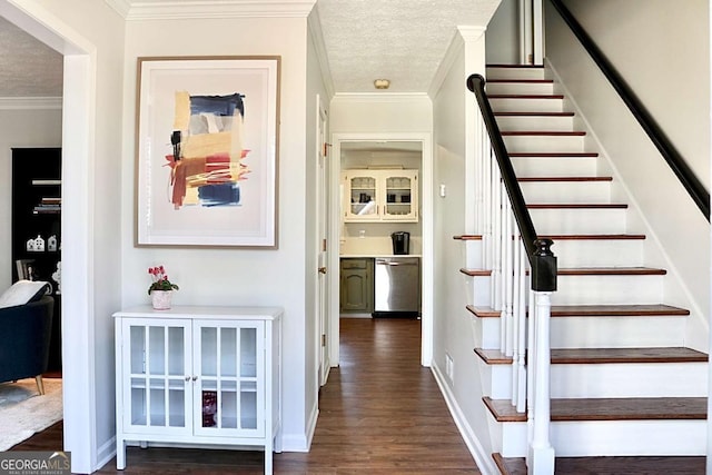 staircase featuring a textured ceiling, crown molding, and wood-type flooring