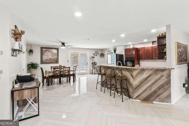 kitchen featuring black oven, a breakfast bar area, light parquet flooring, and fridge