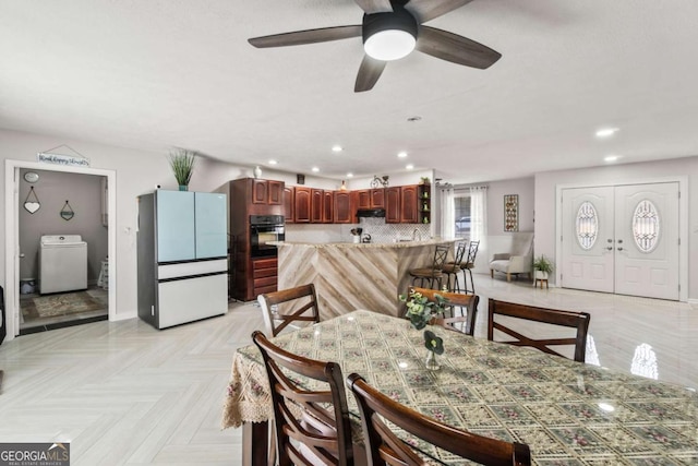 dining room featuring washer / dryer, light parquet flooring, and ceiling fan