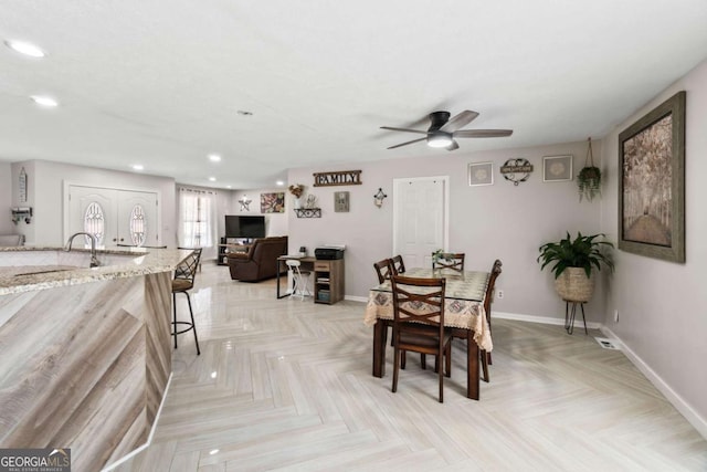 dining room featuring ceiling fan, sink, light parquet floors, and french doors