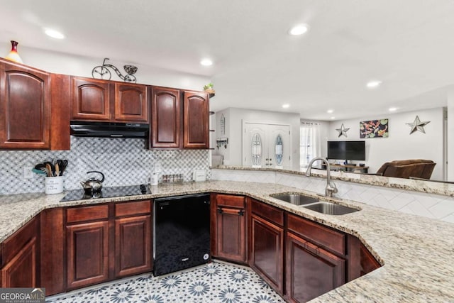 kitchen featuring tasteful backsplash, light stone counters, black appliances, and sink