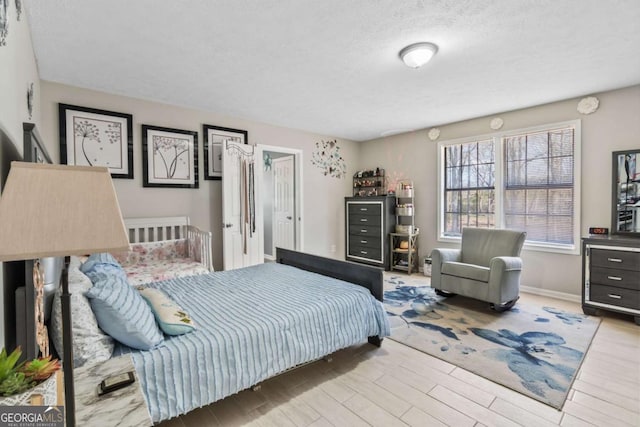 bedroom with light hardwood / wood-style flooring and a textured ceiling