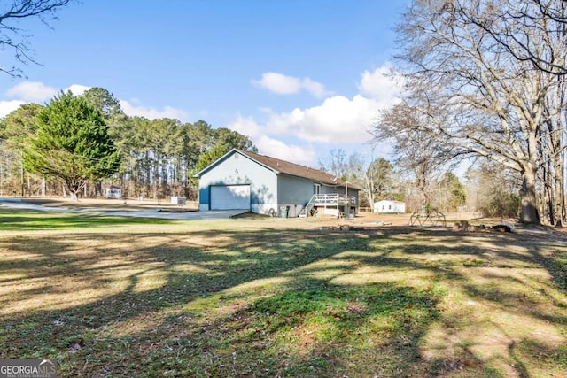 view of yard featuring a garage, an outbuilding, and a deck