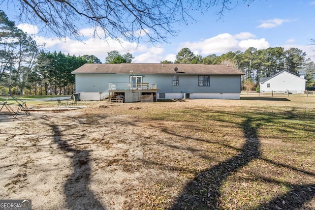 back of house featuring a lawn and a wooden deck