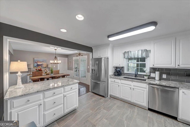 kitchen featuring appliances with stainless steel finishes, tasteful backsplash, sink, pendant lighting, and white cabinets