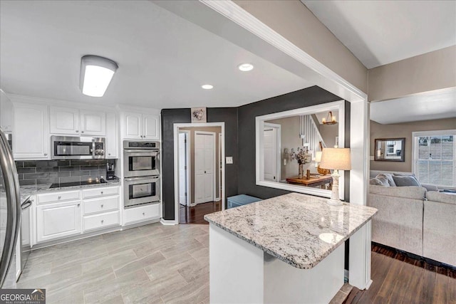 kitchen featuring decorative backsplash, white cabinetry, light stone countertops, and appliances with stainless steel finishes