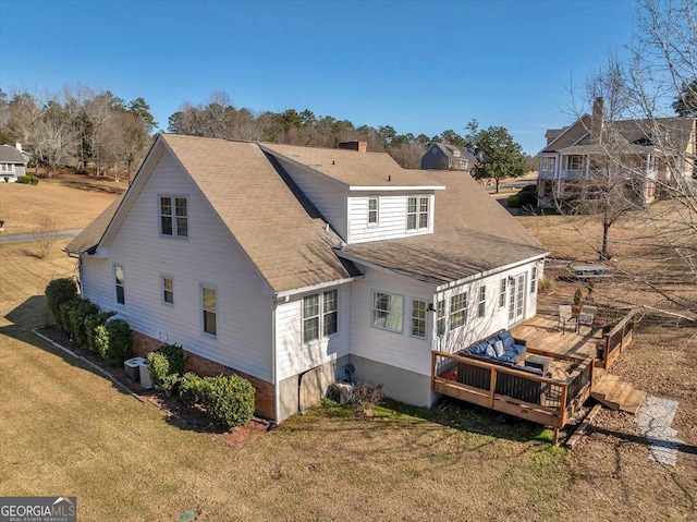 rear view of house featuring central AC, a deck, and a lawn